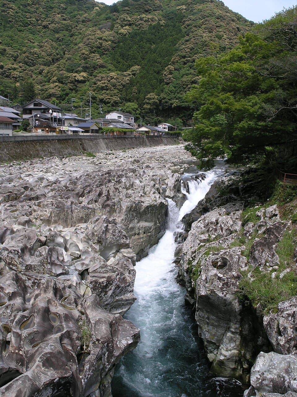 甌穴が連なる川床を水が滑り落ちる奇瀑を橋の上から眺める